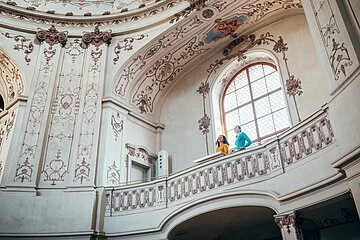 Auf der Empore stehen zwei Frauen und betrachten den herrlichen Kuppelsaal mit den Deckenfresken.