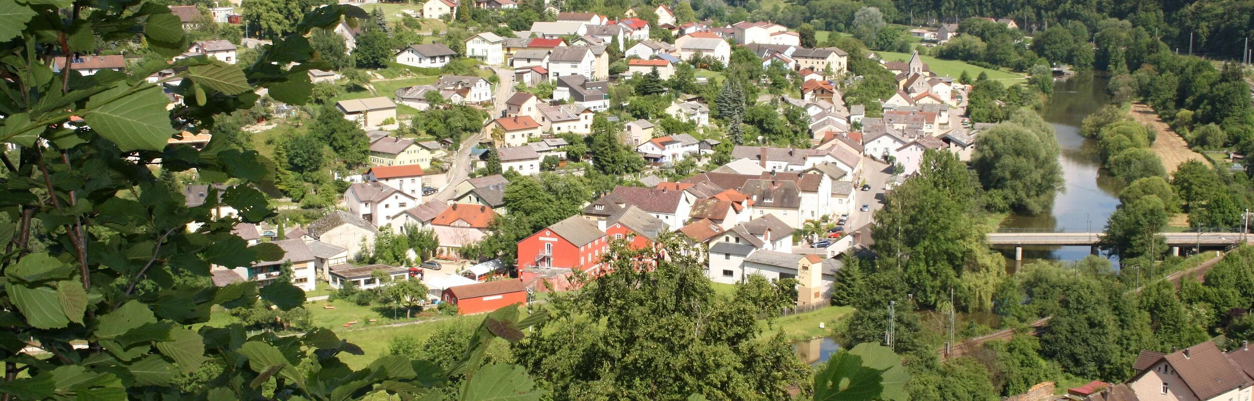 Solnhofen von oben. Eingerahmt von grünen Blättern und dem bewaldeten Hängen.