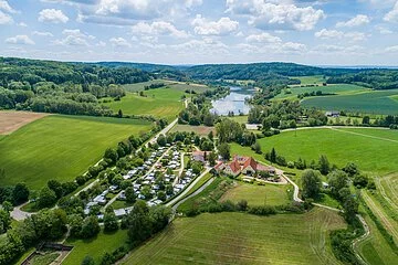 Blick auf den Campingplatz Hasenmühle Der Campingplatz Hasenmühle von oben inmitten grüner Wiesen und Bäumen. Hinter dem Platz ist der Hahnenkammsee zu sehen.