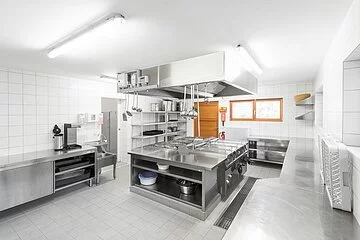 Die Großraumküche des Zeltplatzes ist in weiß und metall schlicht gehalten.