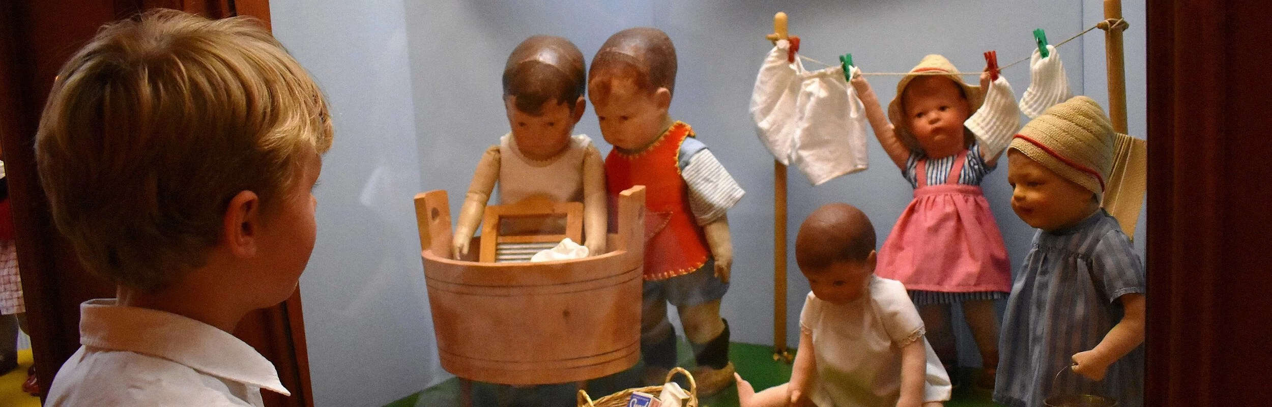 Ein Junge betrachtet eine Puppenszene im Käthe Kruse Puppenmuseum.