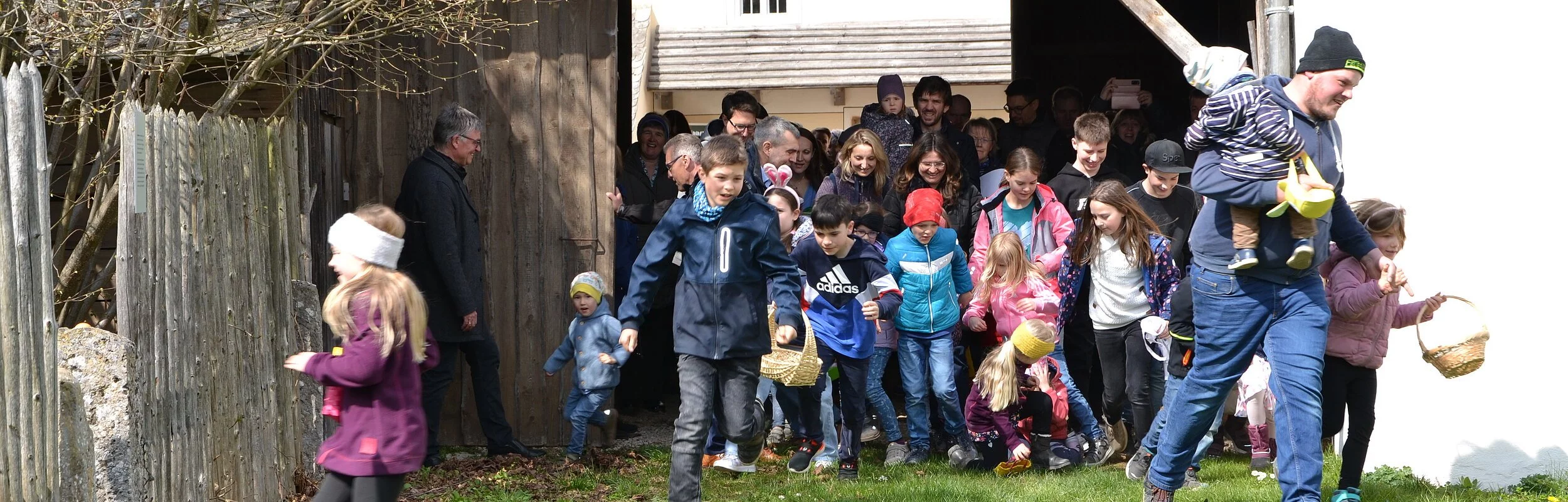 Durchs offene Tor stürmen zahlreich Kinder in den Garten des Jura-Bauernhofmuseums, um die Jagd auf die versteckten Ostereier zu beginnen