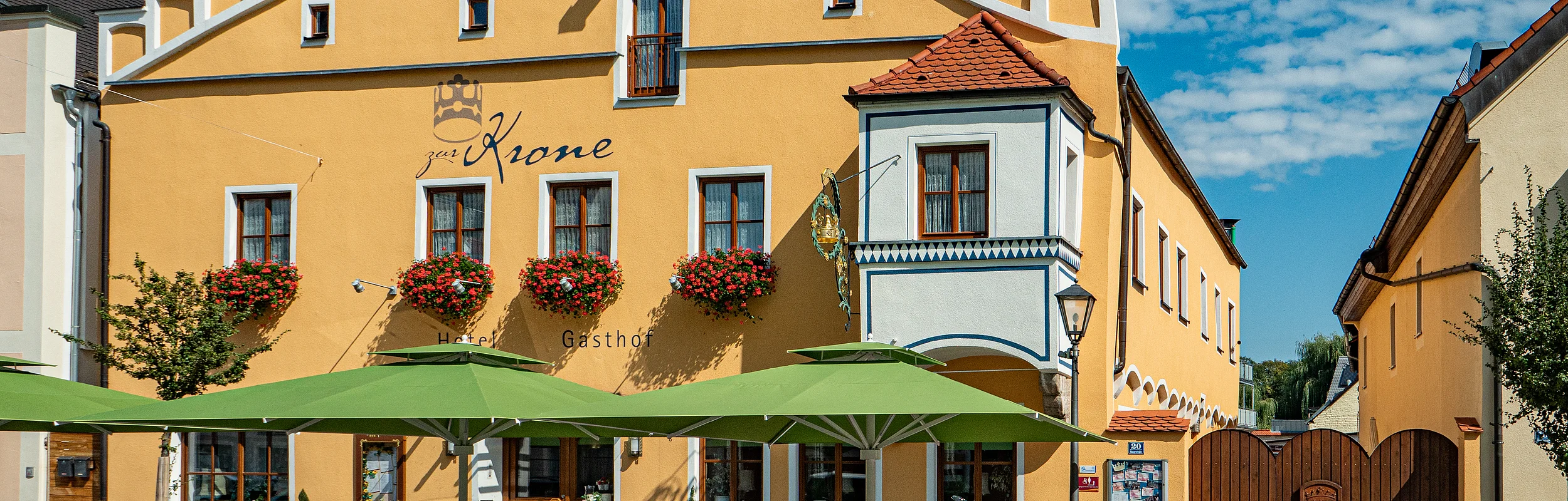 Die Außenansicht des Hotel zur Krone in Beilngries mit Stühlen und Tischen vor dem Gebäude.