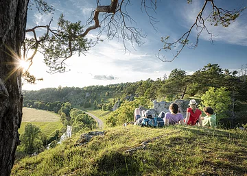 Wanderer bei den 12 Apostel bei Solnhofen Vier Wanderer liegen im grünen auf den 12 Aposteln am Altmühltal-Panoramaweg. Sie genießen den Sonnenuntergang und den Blick ins Tal.