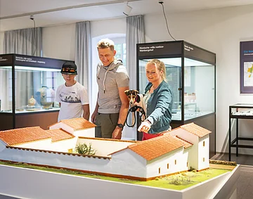 Museum Vor- und Frühgeschichte Eine Familie besucht die Abteilung der Abteilung Vor- und Frühgeschichte im Museum. Sie Blicken auf eine Nachbildung einer sogenannten Villa Rustica.