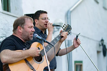Konzert in der Aktivmühle Solnhofen Zwei Männer singen bei einem Konzert in ein Mikrofon. Einer der beiden spielt Gitarre.