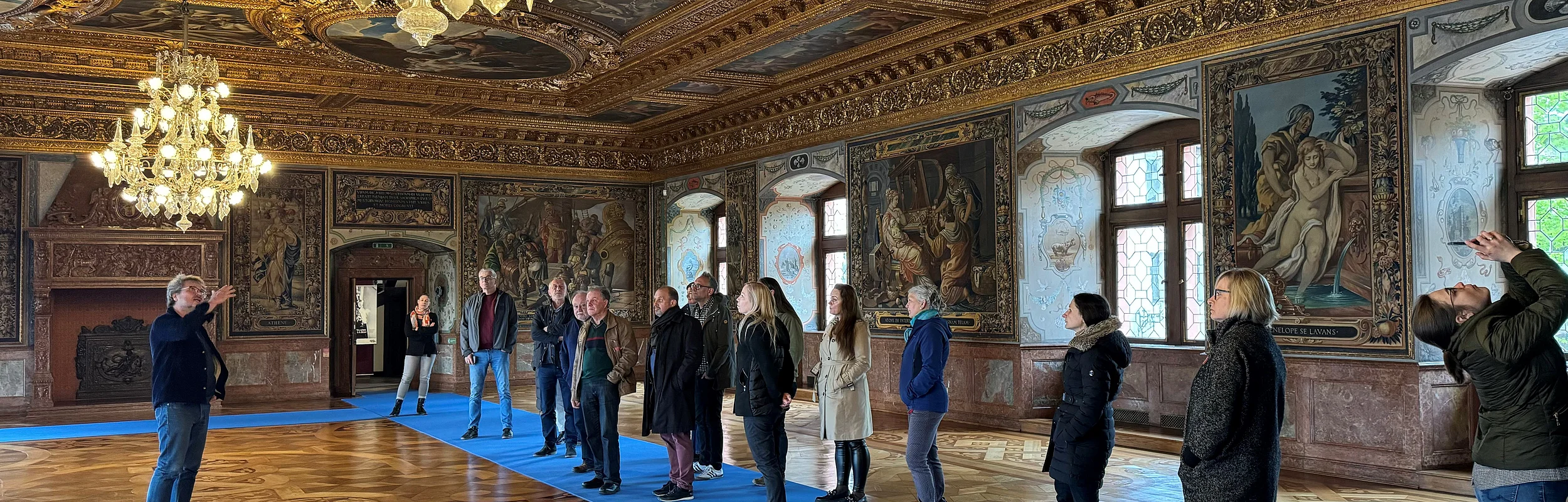Das Foto zeigt eine Führung durch den Prunksaal im Schloss Ratibor in Roth durch den Museumsleiter für ca. 16 Museumskollegen.