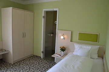 Ein Zimmer mit grünen Wänden, Schrank und Bett im Hotel zur Krone.