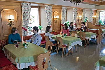 Das Gastzimmer im Hotel zur Krone mit drei Tischen und Personen.