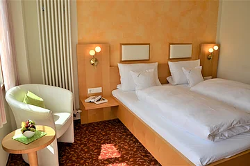 Ein Gästezimmer im Hotel zur Krone mit Bett, Stuhl und kleinem Tisch.