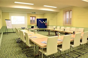 Ein Seminarraum im Hotel zur Krone mit weißen Stühlen in U-Form.