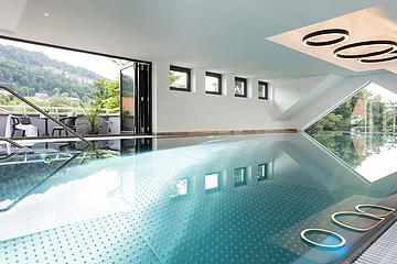 Das Schwimmbad ist hell ausgeleuchtet mit Fokus auf das türkisfarbene Wasser.