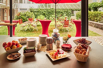 Kleines Frühstücksbuffet im Freien mit einer Auswahl an Obst, Gebäck und Snacks.