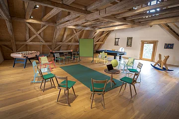 Einige Stühle die im Kreis aufgestellt sind mit einer Tafel, im Dachgeschoss.