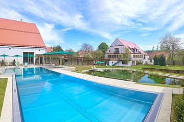 Große Outdoor Poolanlage mit Grünfläche, Liegestühlen und Sonnenschirmen.