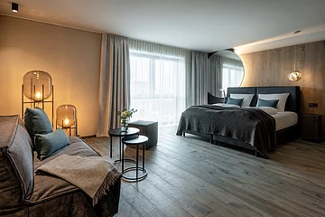 Das modern und dunkel eingerichtete Schlafzimmer hat einige Details aus Holz und ist gut beleuchtet.