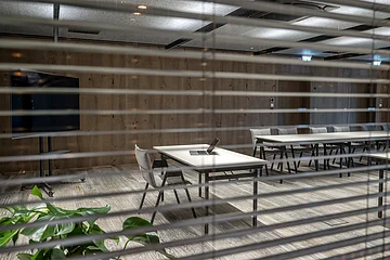 Die grauen Stühle sind um einen weißen langen Tisch ausgerichtet. Der Raum ist minimalistisch eingerichtet.