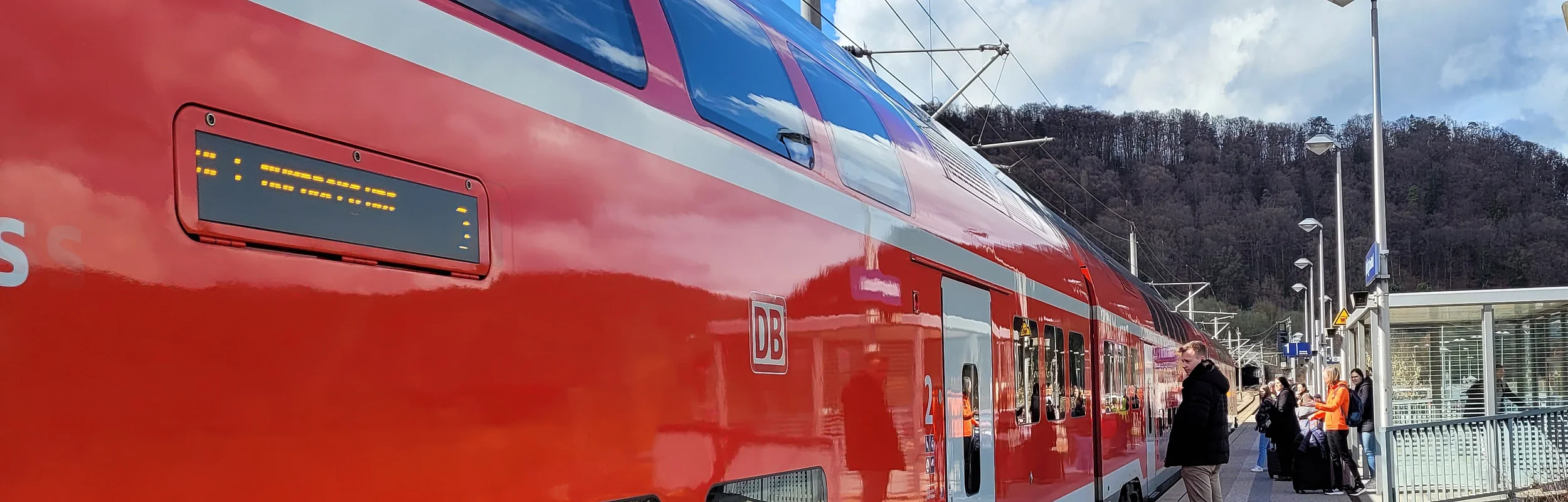 Eine Regionalbahn hat am Gleis gehalten und Reisende warten darauf, dass sich die Türen öffnen.