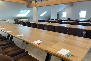 Die Holztische sind nebeneinander aufgereiht, mit braunen Sesseln.