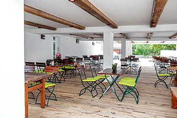 Der überdachte Biergarten ist ausgestattet mit Tischen und Stühlen.