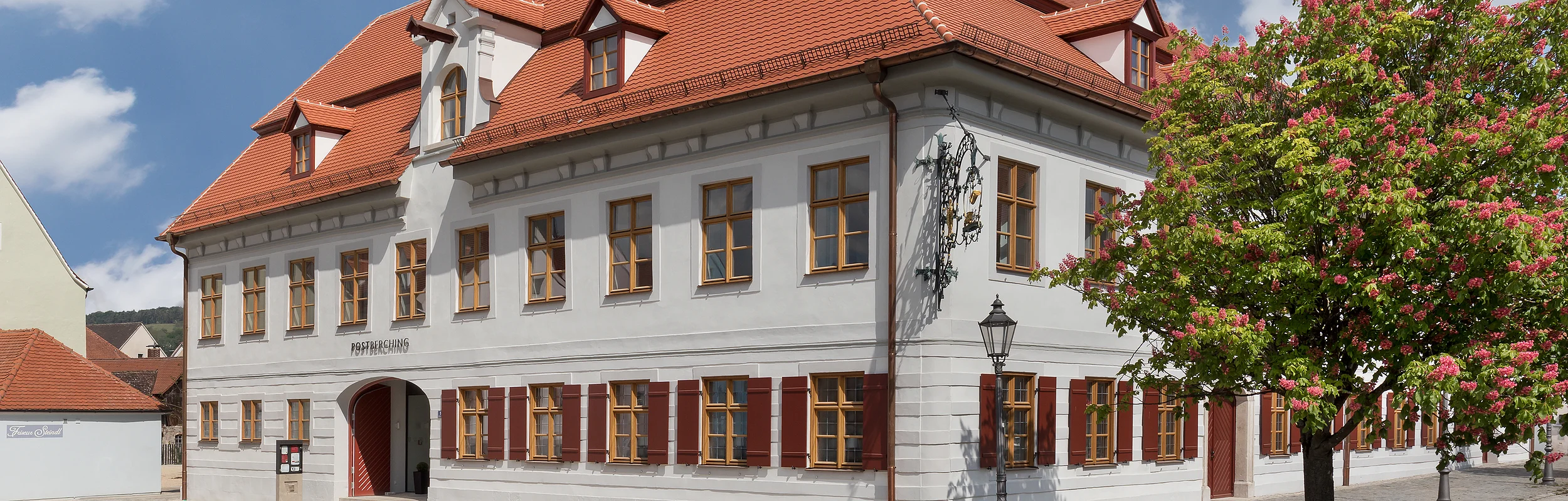 Ein gepflegtes Gebäude mit vielen Fenstern und weinroten Fensterläden.