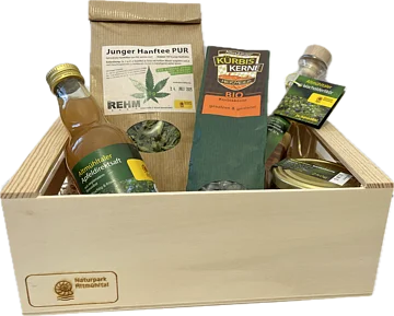 Holzkiste mit verschiedenen regionalen Produkten: Apfelsaft, Hanftee, Kürbiskerne, Wacholderlikör und Honig.