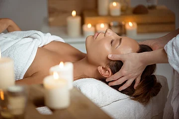 Relaxtage im Landhotel Zur Jurahöhe Person erhält Kopfmassage in einem Spa, umgeben von brennenden Kerzen.