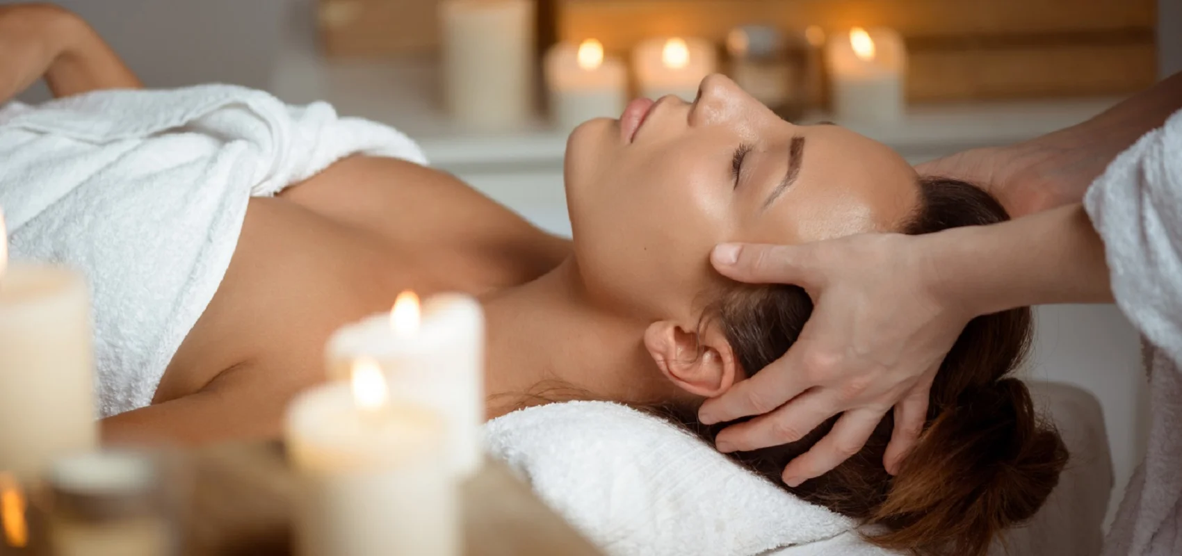 Relaxtage im Landhotel Zur Jurahöhe Person erhält Kopfmassage in einem Spa, umgeben von brennenden Kerzen.
