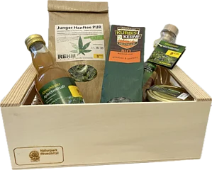 Holzkiste mit verschiedenen regionalen Produkten: Apfelsaft, Hanftee, Kürbiskerne, Wacholderlikör und Honig.