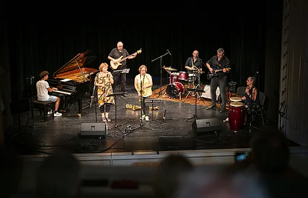 Jazzkonzert in Neuburg an der Donau Eine sechsköpfige Band spielt auf einer Bühne. Ein Pianist, Sängerin, Saxophonistin, Bassist, Schlagzeuger und Gitarrist sind zu sehen.