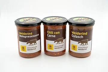 Drei Gläser mit Weiderind Bolognesesauce, Chili con Carne und Weiderind Gulasch vor weißem Hintergrund.