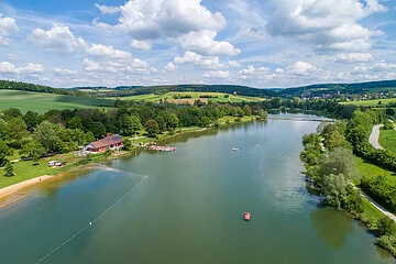 Hahnenkammsee von Süden nach Norden mit Strandanlage links, Seeterasse und Badestrand