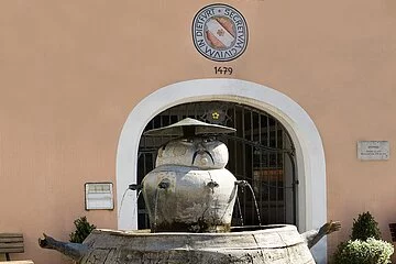 Chinesenbrunnen vorm Rathaus im Mittelpunkt, ganz vorne links Blumen.